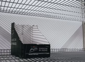Pusty kartonowy box ekspozycyjny na metalowej półce sklepowej.